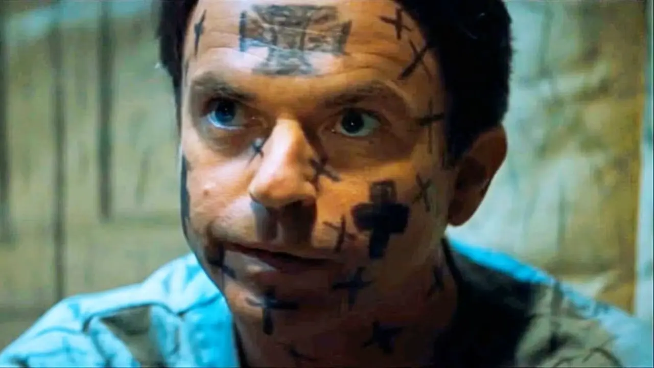 Sam Neill en un manicomio con cruces dibujadas en el rostro en En la boca de la locura (1) Sam Neill en un manicomio con cruces dibujadas en el rostro en En la boca de la locura (1)