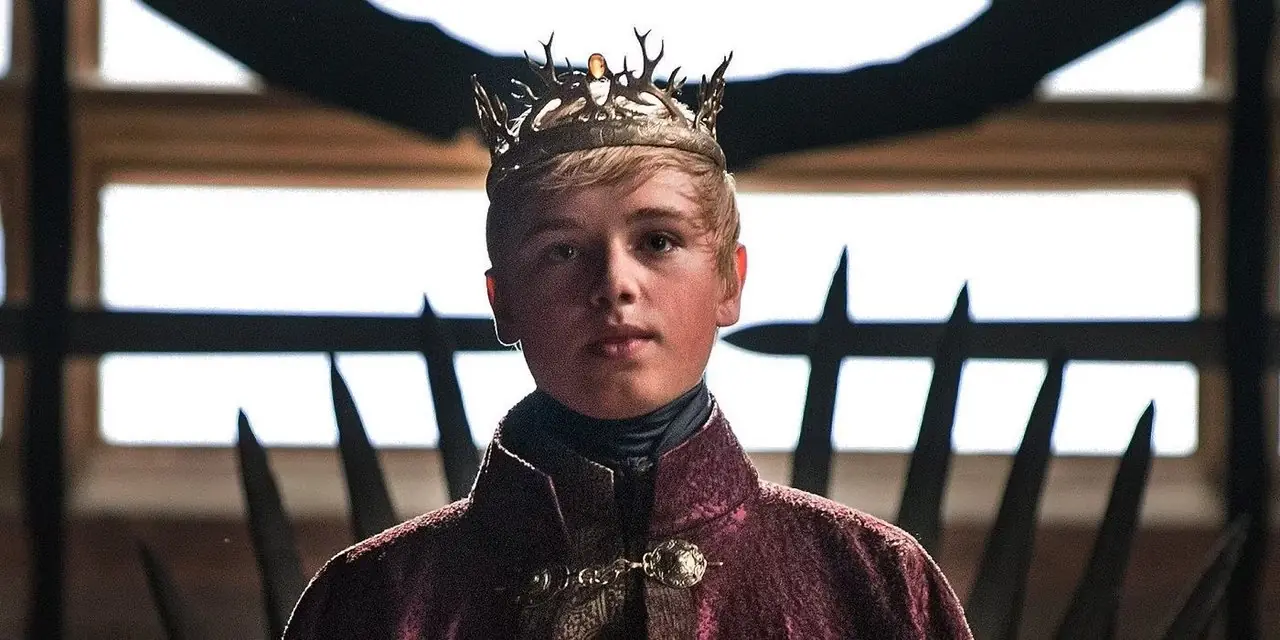 Tommen Baratheon trägt seine Krone und steht in Game of Thrones vor dem Eisernen Thron. Tommen Baratheon trägt seine Krone und steht in Game of Thrones vor dem Eisernen Thron.