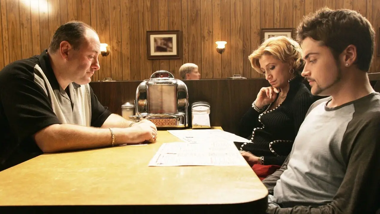 Tony (James Gandolfini), Carmela (Edie Falco) e A.J. (Robert Iler) seduto a un tavolo da pranzo in I Soprano, Made in America. Tony (James Gandolfini), Carmela (Edie Falco) e A.J. (Robert Iler) seduto a un tavolo da pranzo in I Soprano, Made in America.