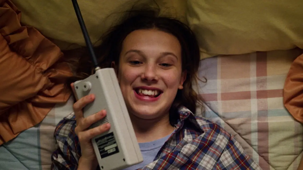 Jedenastka Millie Bobby Brown rozmawia przez telefon i śmieje się w „Stranger Things”. Jedenastka Millie Bobby Brown rozmawia przez telefon i śmieje się w „Stranger Things”.