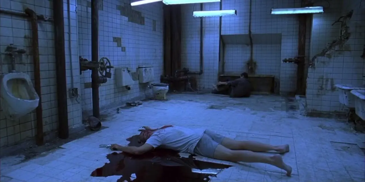 Kramer deitado no centro do banheiro em Saw