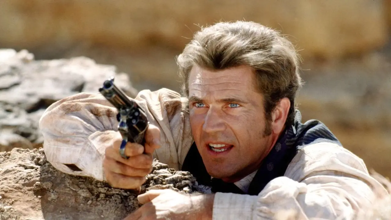 Mel Gibson jako Maverick zwisający z klifu w Maverick (1994) Mel Gibson jako Maverick zwisający z klifu w Maverick (1994)