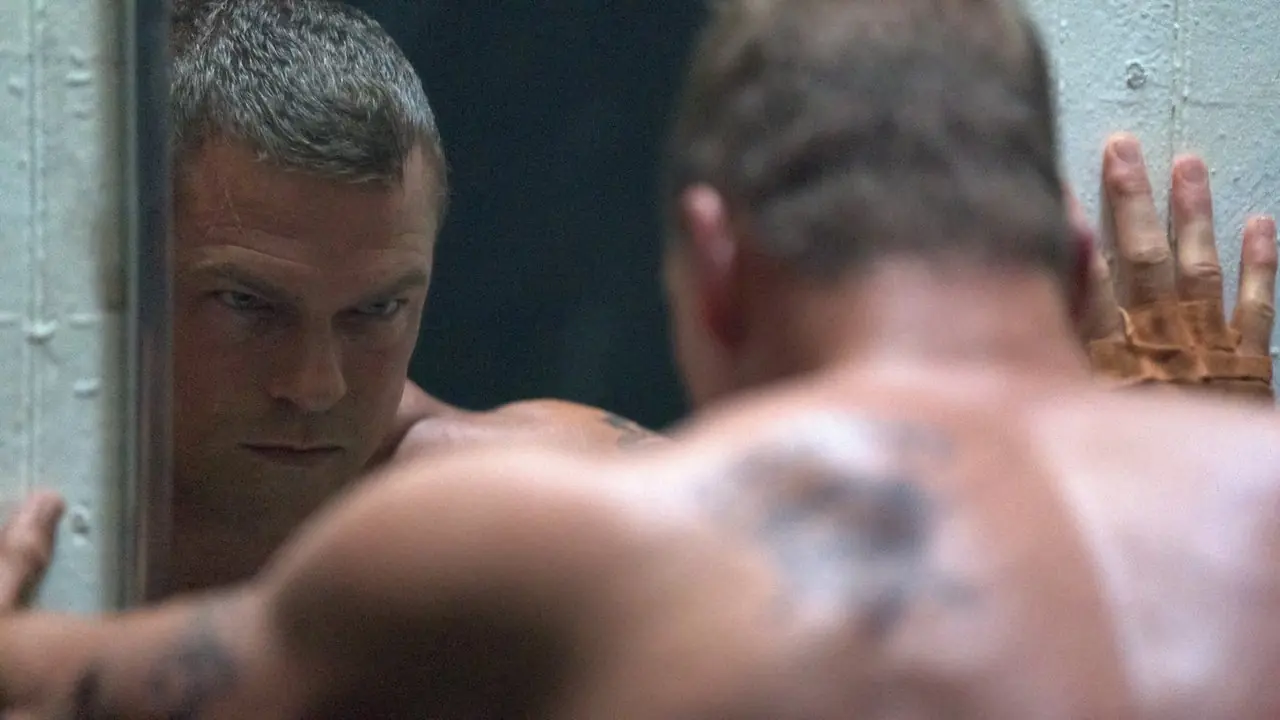 John di Alan Ritchson che si guarda con rabbia allo specchio senza maglietta a Motor City