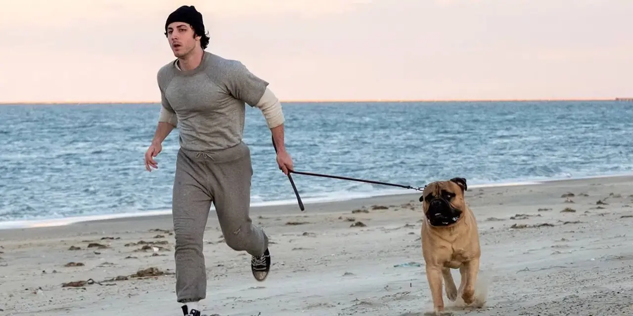 Sylvester Stallone und ein Hund laufen in „I Play Rocky“ an einem Strand