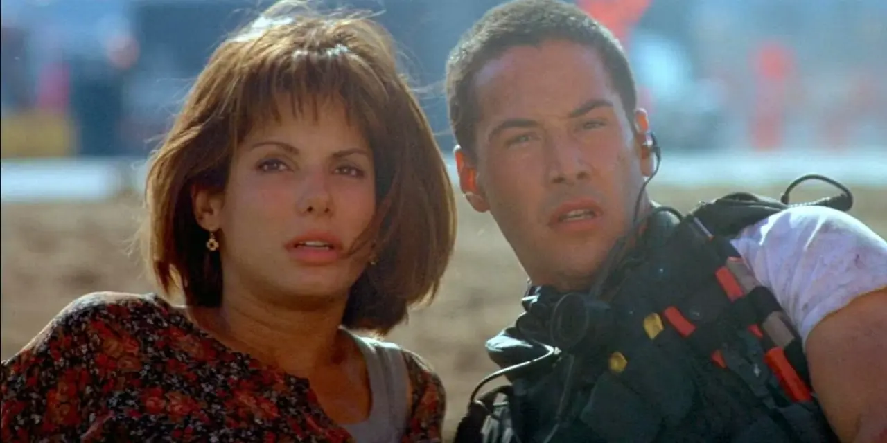 Keanu Reeves ve Sandra Bullock Speed'de yerde duruyor ve uzaklara bakıyorlar