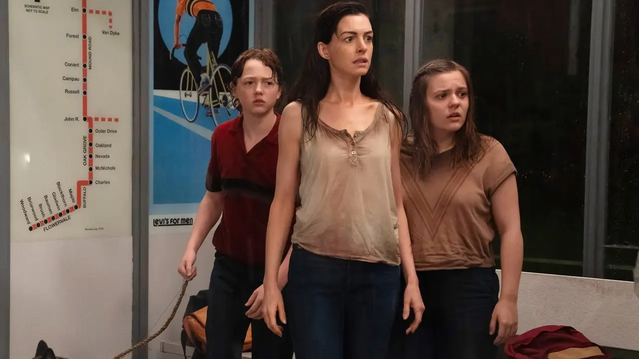 Brian de Christian Convery, Denise de Anne Hathaway y Audrey de Maisy Stella parecen preocupados en una parada de autobús en The End of Oak Street