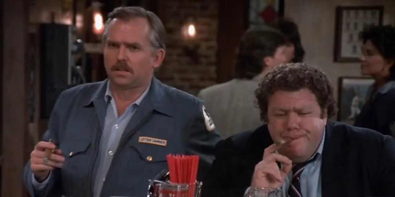 Cliff Clavin (John Ratzenberger) y Norm Peterson (George Wendt) fumando un cigarro en Cheers temporada 4, episodio 18