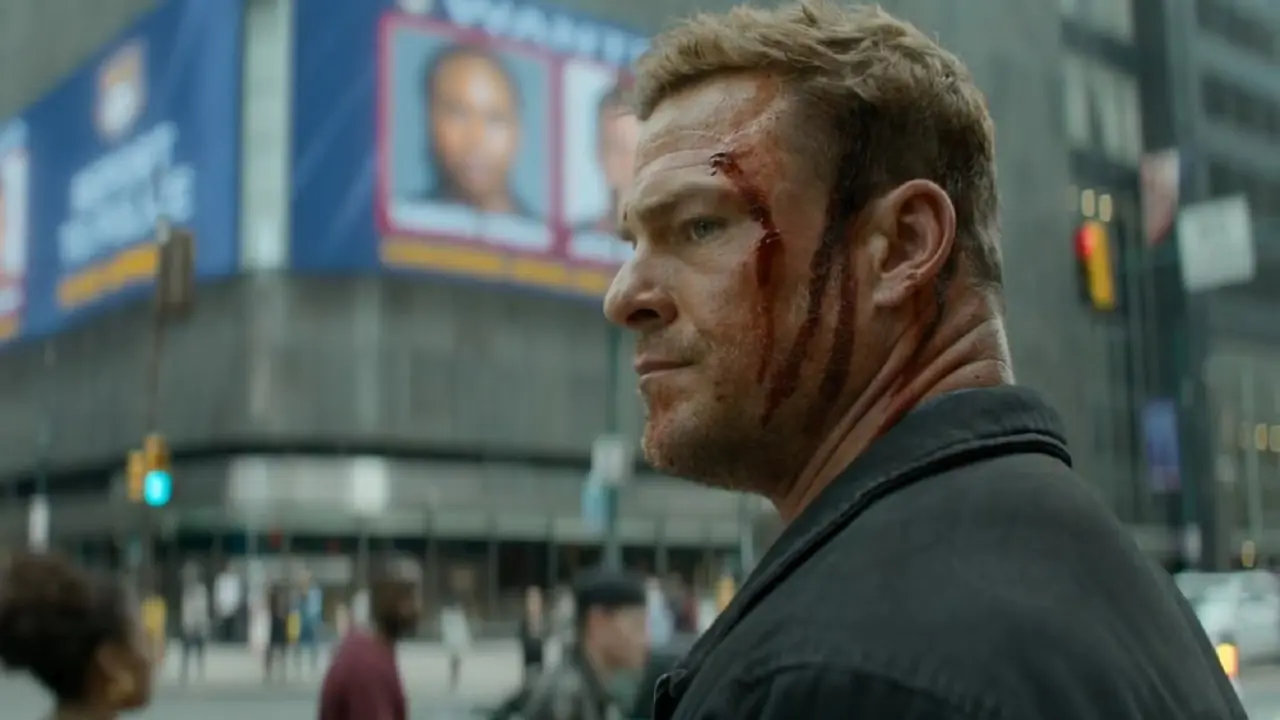 艾伦·里奇森 (Alan Ritchson) 在通缉海报前饰演血淋淋的雷奇 (Racher)。 艾伦·里奇森 (Alan Ritchson) 在通缉海报前饰演血淋淋的雷奇 (Racher)。