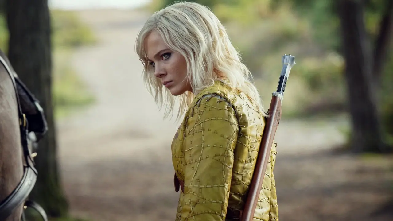 Ciri (Freya Allan) in piedi di lato e guarda lontano con un'arma sulla schiena nella stagione 4 di The Witcher Ciri (Freya Allan) in piedi di lato e guarda lontano con un'arma sulla schiena nella stagione 4 di The Witcher