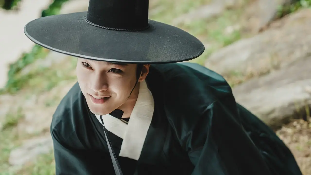 Ein Mann in Kleidung aus der Joseon-Zeit grinst dunkel im Ostpalast.