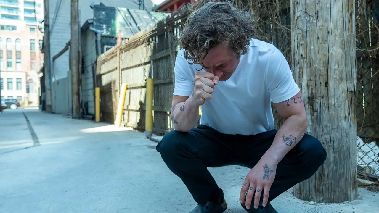 Una imagen de Jeremy Allen White agachado en el suelo con una camiseta blanca y pantalones de vestir durante el episodio 9 de la temporada 2 de The Bear.