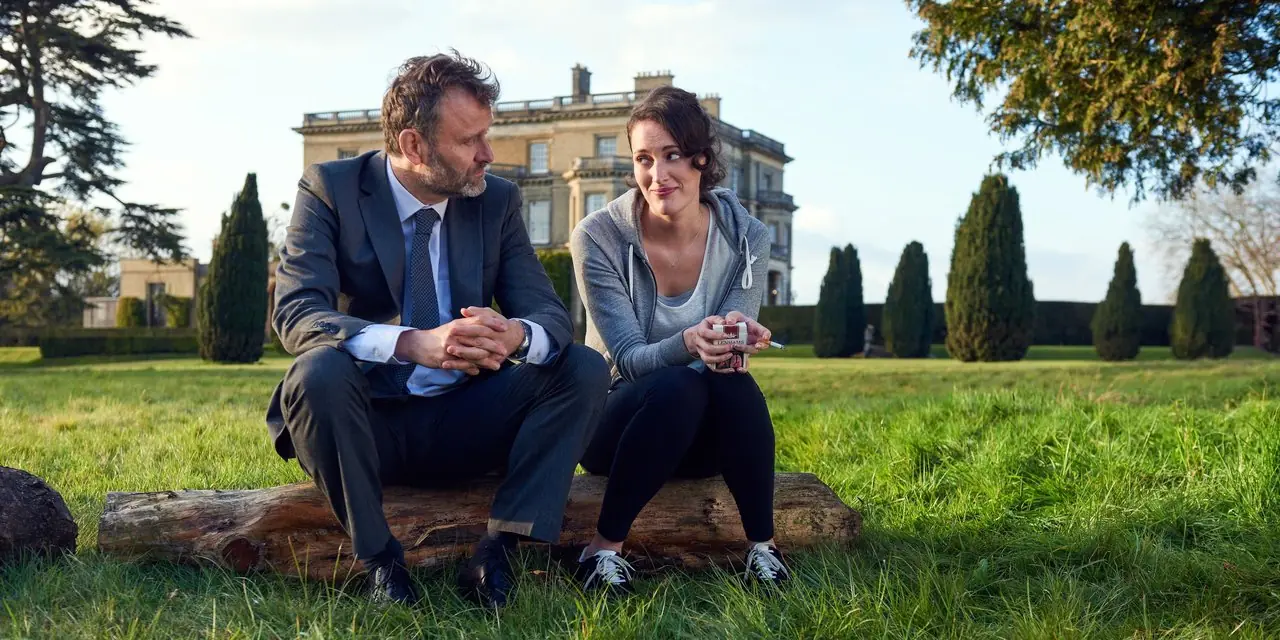Banksjefen (Hugh Dennis) snakker med Fleabag (Phoebe Waller-Bridge) på en tømmerstokk i Fleabag.