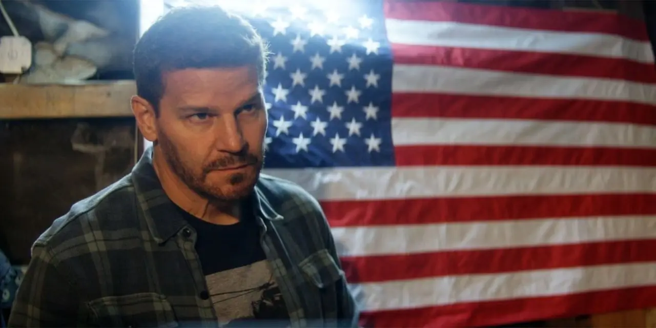 David Boreanaz como Jason Hayes en la final del equipo SEAL, de pie frente a una bandera estadounidense
