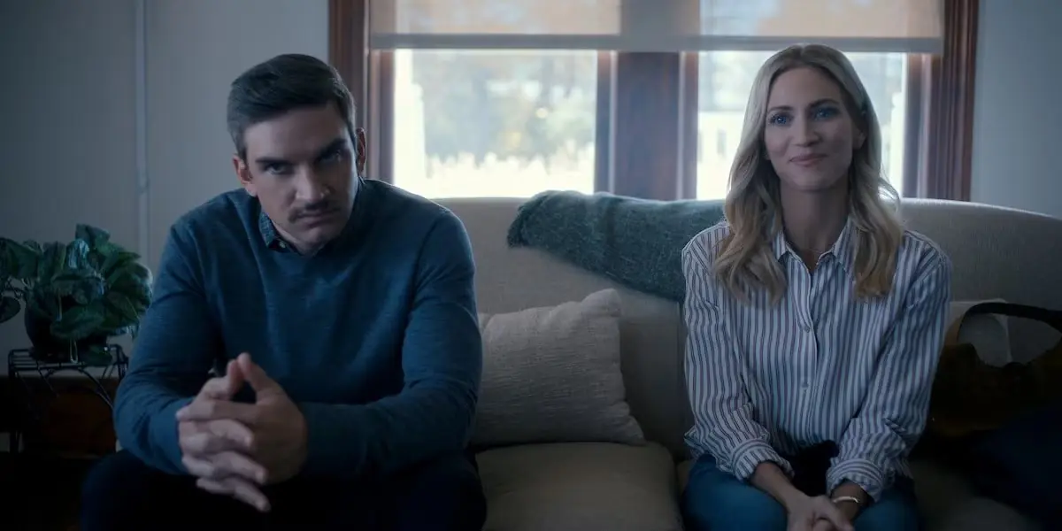Een stel zittend op een bank in The Hunting Wives