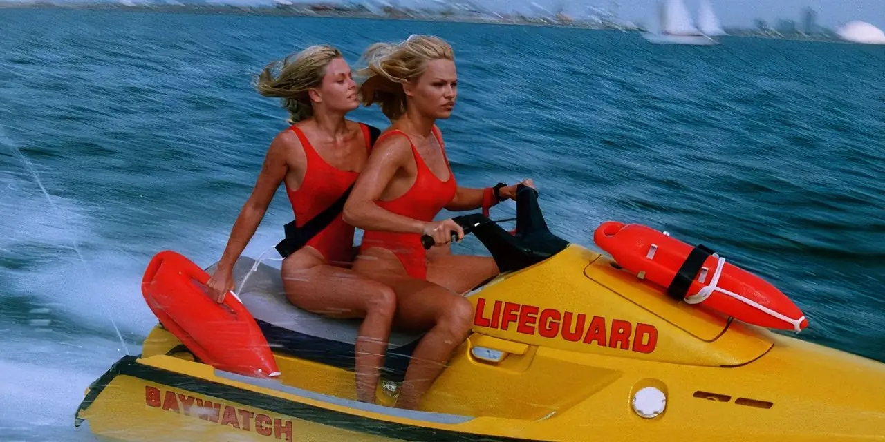 Nicole Eggert como Summer Quinn y Pamela Anderson como C.J. Parker montando una moto de agua en Baywatch. Nicole Eggert como Summer Quinn y Pamela Anderson como C.J. Parker montando una moto de agua en Baywatch.