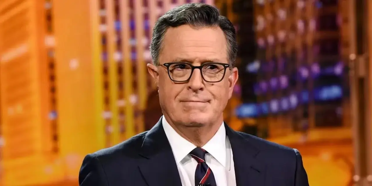 Stephen Colbert guarda severamente la telecamera con un leggero sorriso sul viso in The Late Show